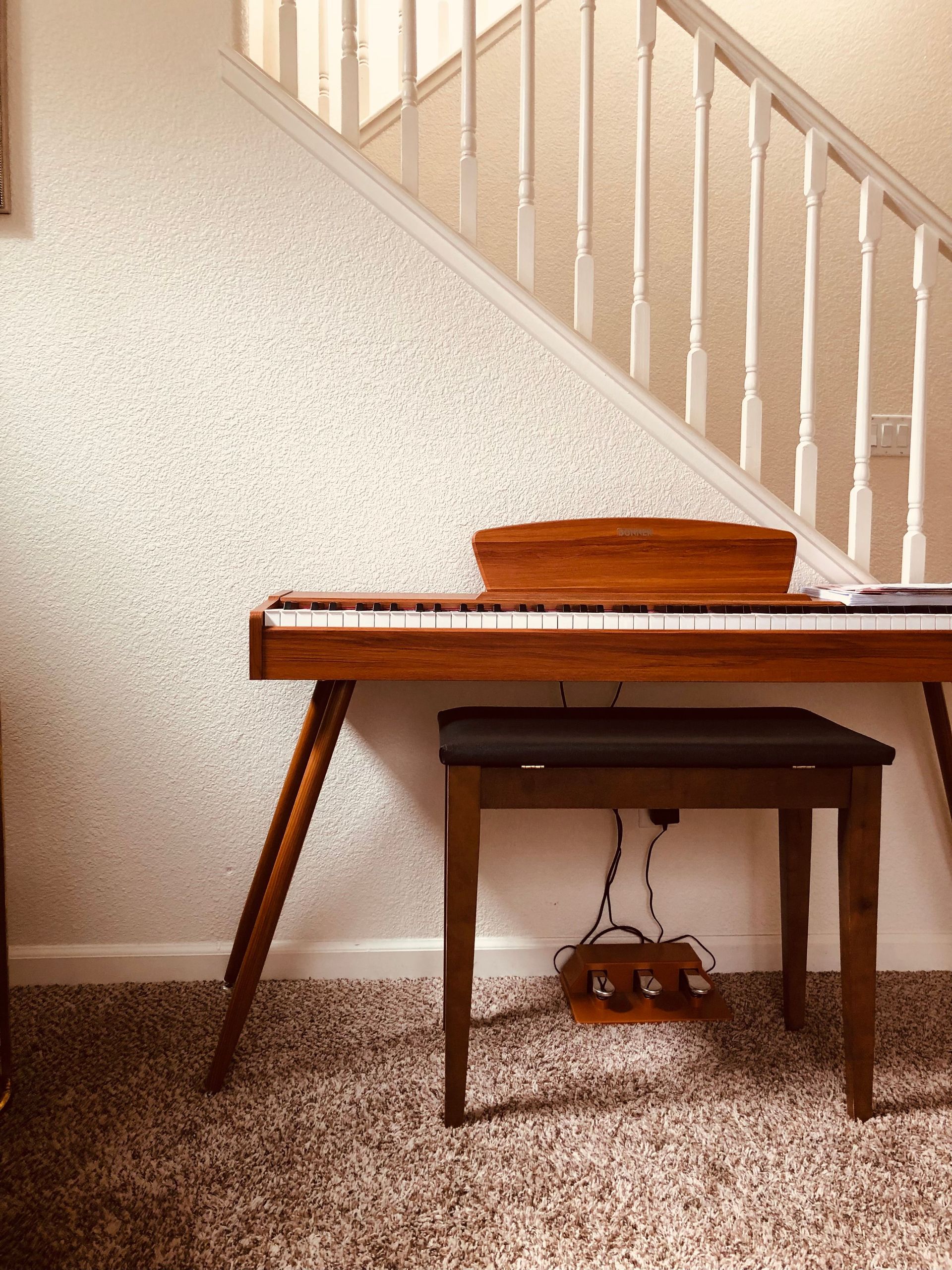Minimalist home with wooden keyboard piano, cozy carpet, and neutral tones.
