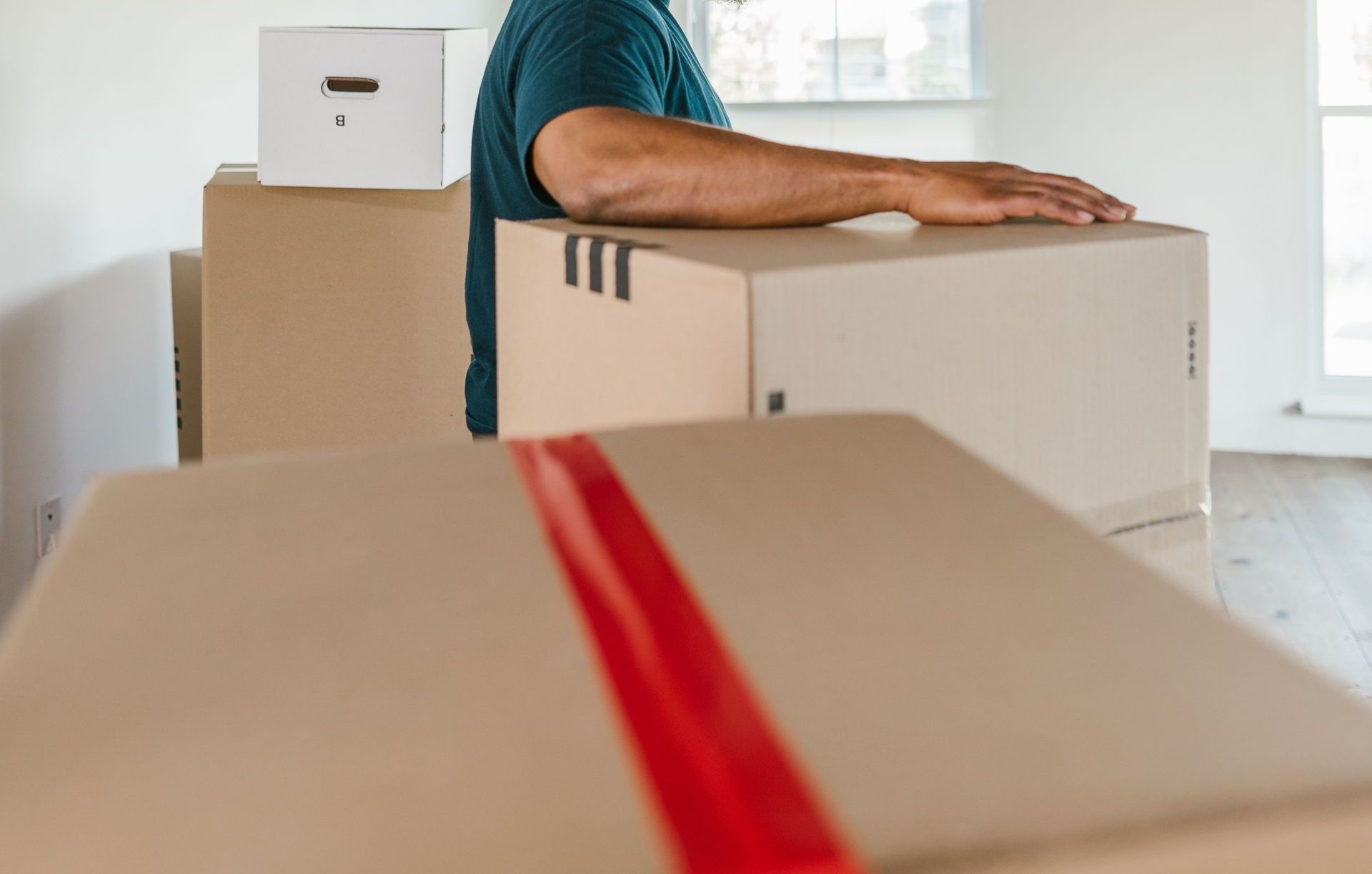 Man handling moving boxes in a spacious, modern room during relocation.